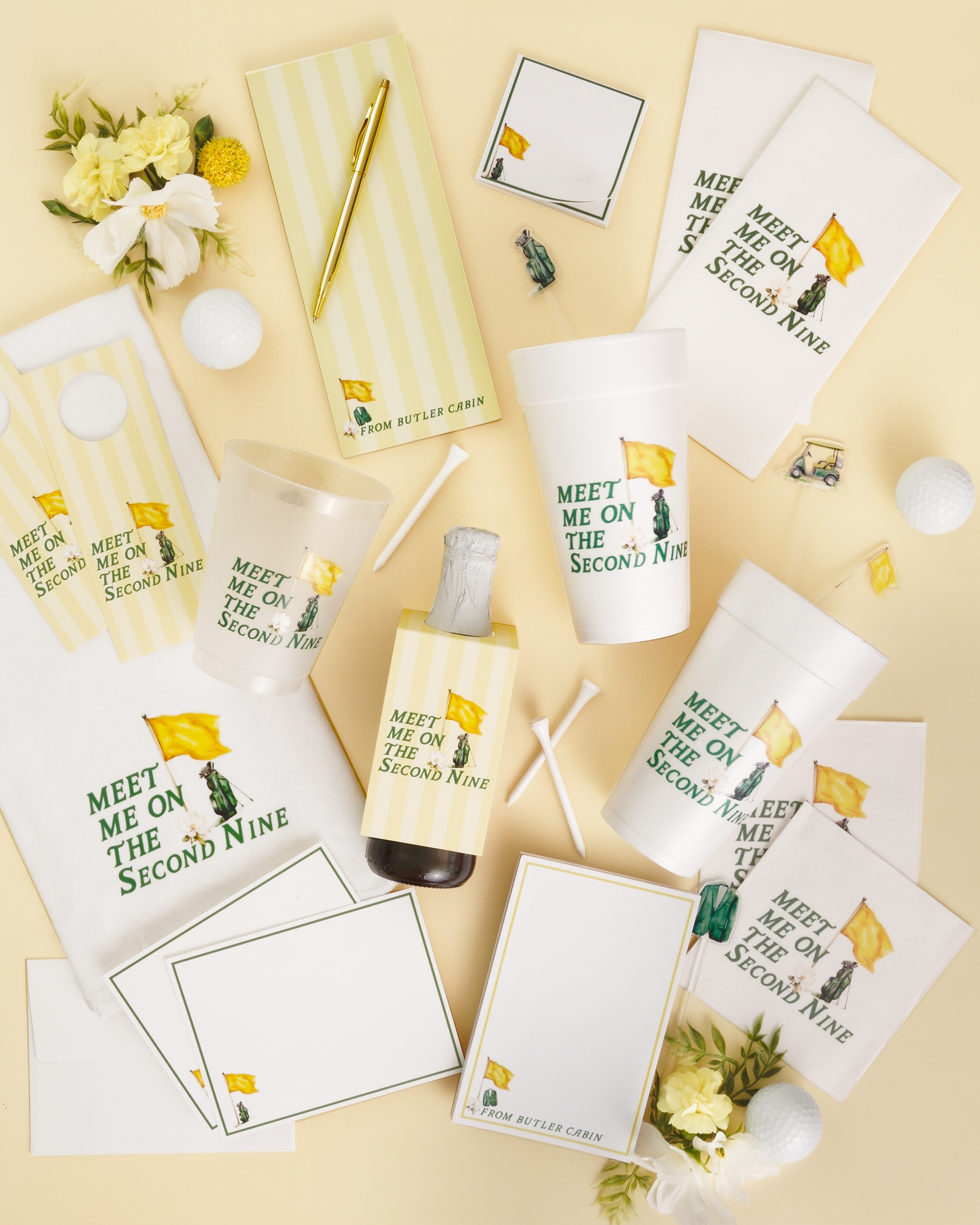 various items related to golf, including a cup, a pen, a bottle, a golf ball, and some flowers. The items are arranged in a casual manner, suggesting they are part of a collection or a display.