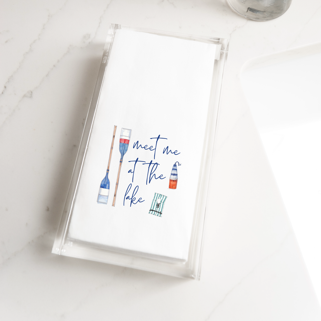 a napkin with a hand-drawn illustration of a boat and a bottle, along with the text "Meet me at the lake".