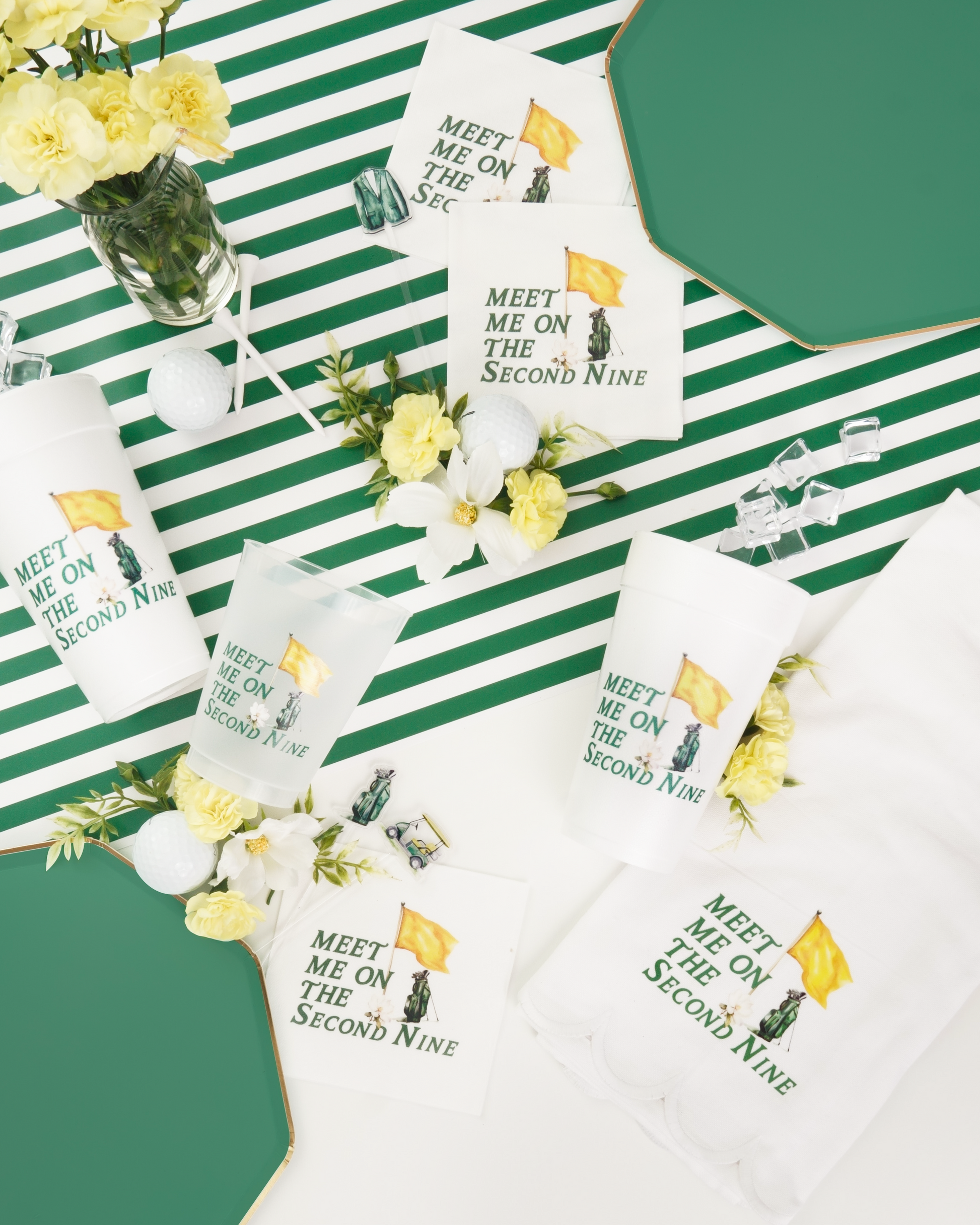 a collection of items, including cups, plates, and flowers, arranged on a striped tablecloth. The text on the items reads "Meet Me on the Second Nine", suggesting a theme or event related to the number nine.